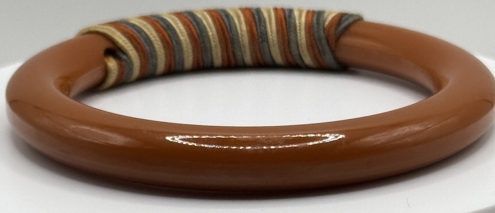 Red/white/blue string-wrapped, rust-colored Bakelite bracelet; tested