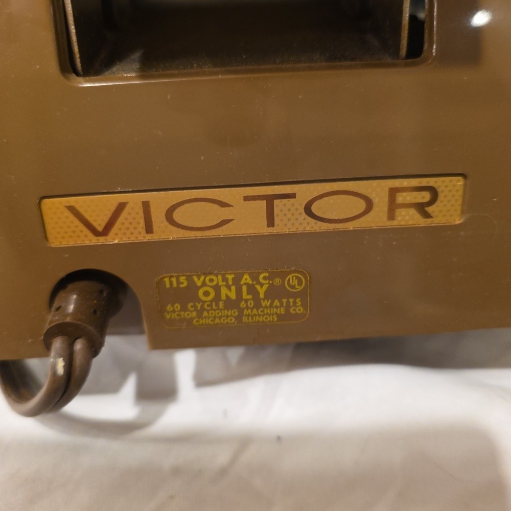 Vintage Victor Champion mechanical adding machine with a paper roll.