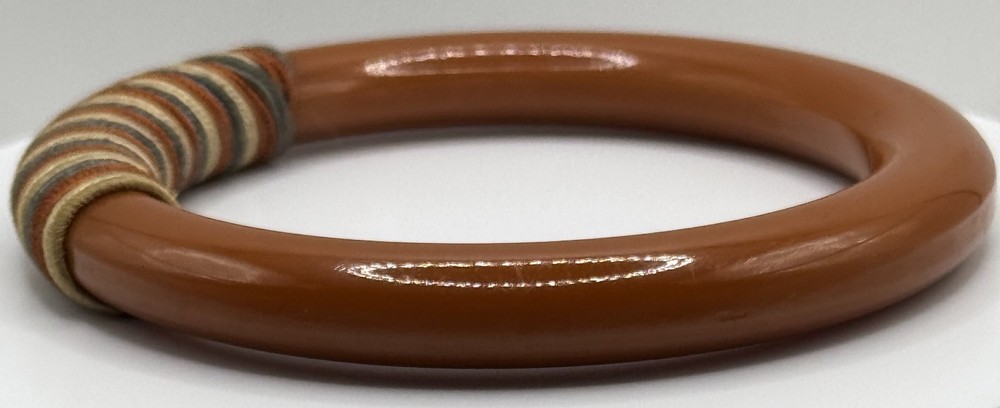 Red/white/blue string-wrapped, rust-colored Bakelite bracelet; tested