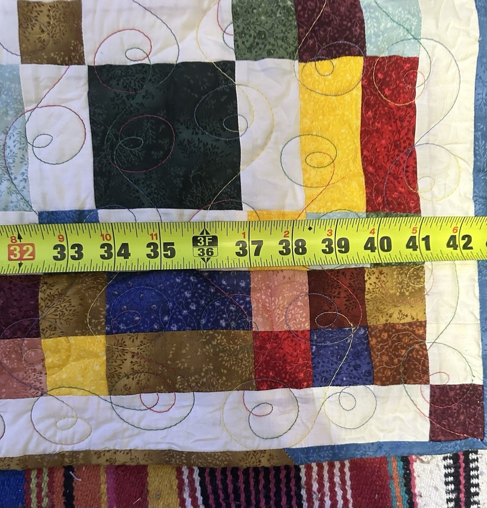 A handmade patchwork quilt with a square block design and visible quilting.