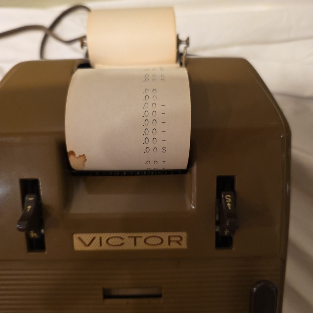 Vintage Victor Champion mechanical adding machine with a paper roll.