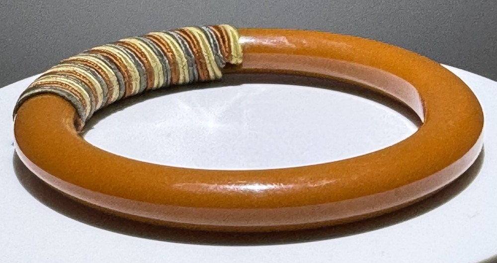 Red/white/blue string-wrapped, rust-colored Bakelite bracelet; tested