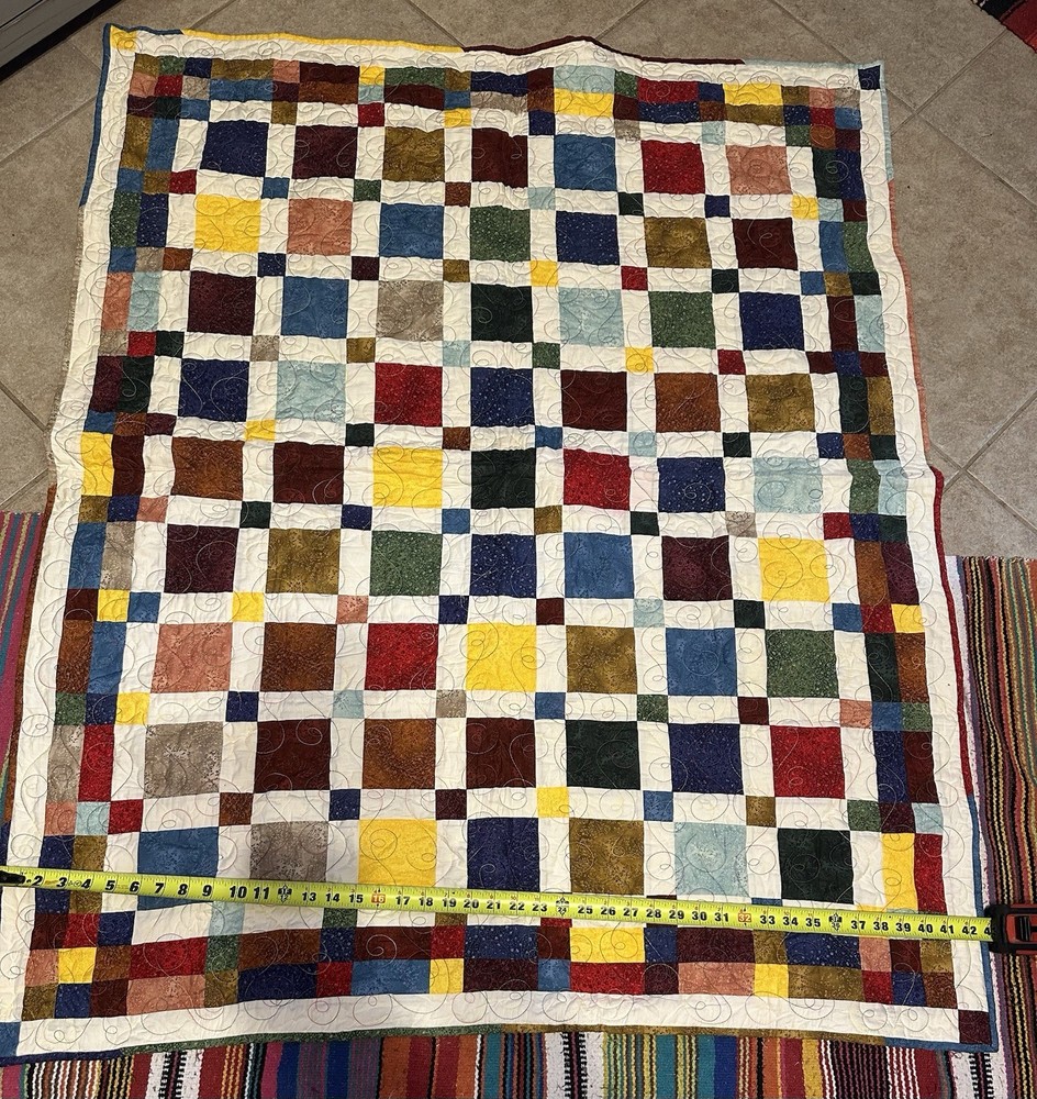 A handmade patchwork quilt with a square block design and visible quilting.