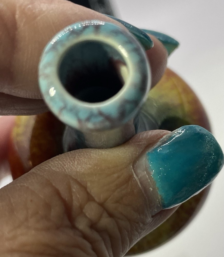 a small, multicolored, drip-glazed ceramic vase.