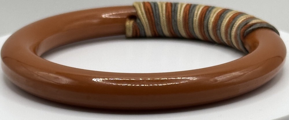 Red/white/blue string-wrapped, rust-colored Bakelite bracelet; tested