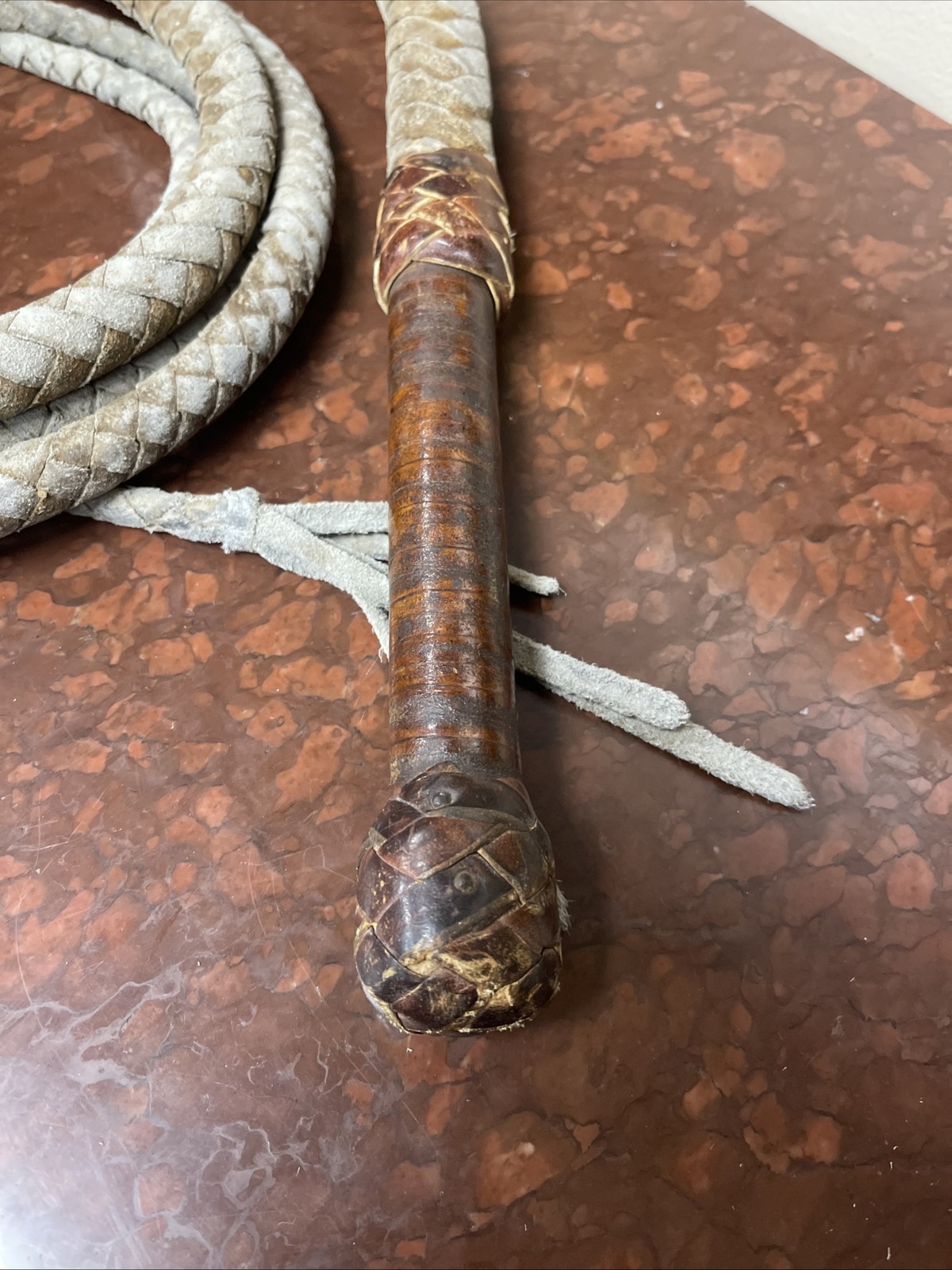 Vintage braided leather bullwhip with a patterned handle.