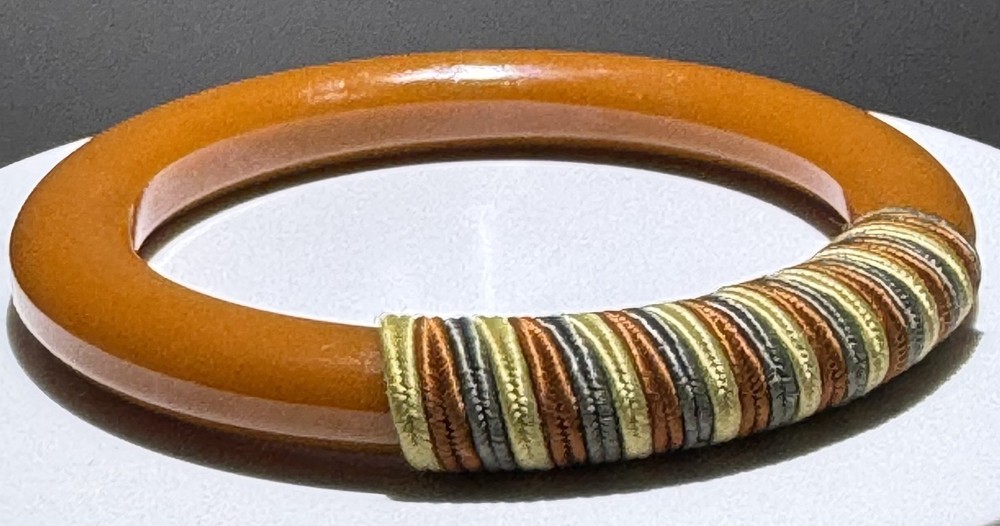 Red/white/blue string-wrapped, rust-colored Bakelite bracelet; tested