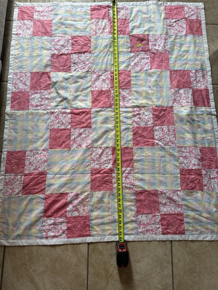 Handmade patchwork quilt with floral, plaid, and pink fabrics.