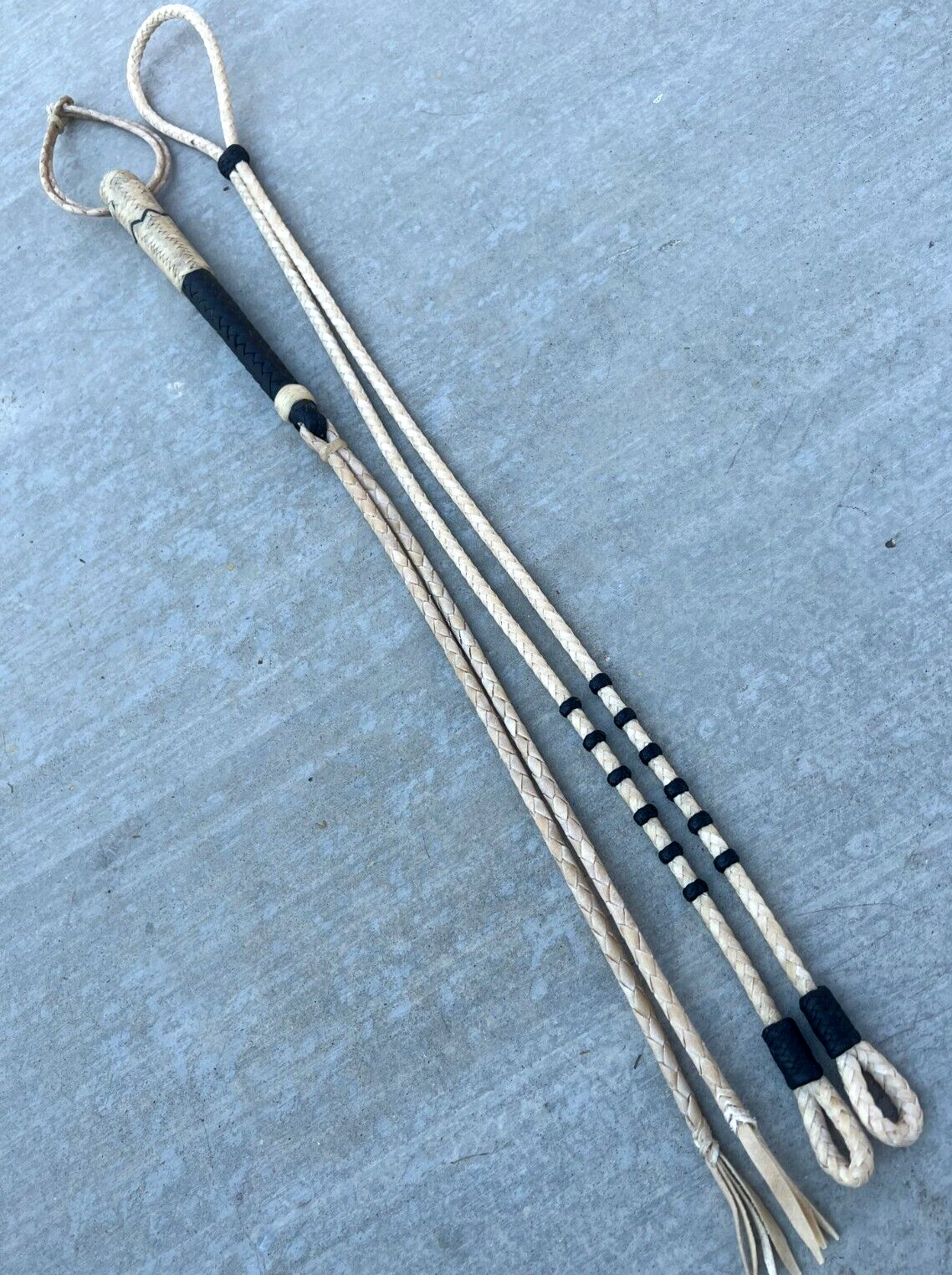 SET OF RAWHIDE REINS AND HORSE QUIRT, SET DE CUARTA CHARRA Y RIENDAS DE CUERO