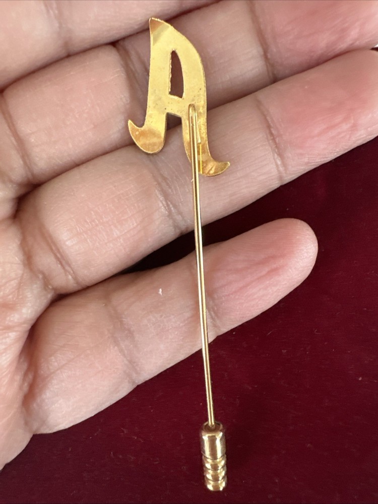 gold-tone monogram lapel pin features a cursive letter 'A' design.