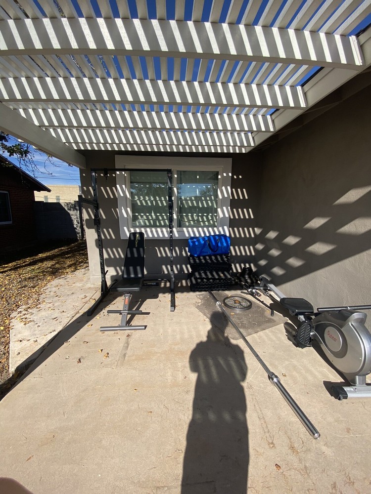 Squat Rack With Bench, Weights, Two Barbells, And A Rowing Machine