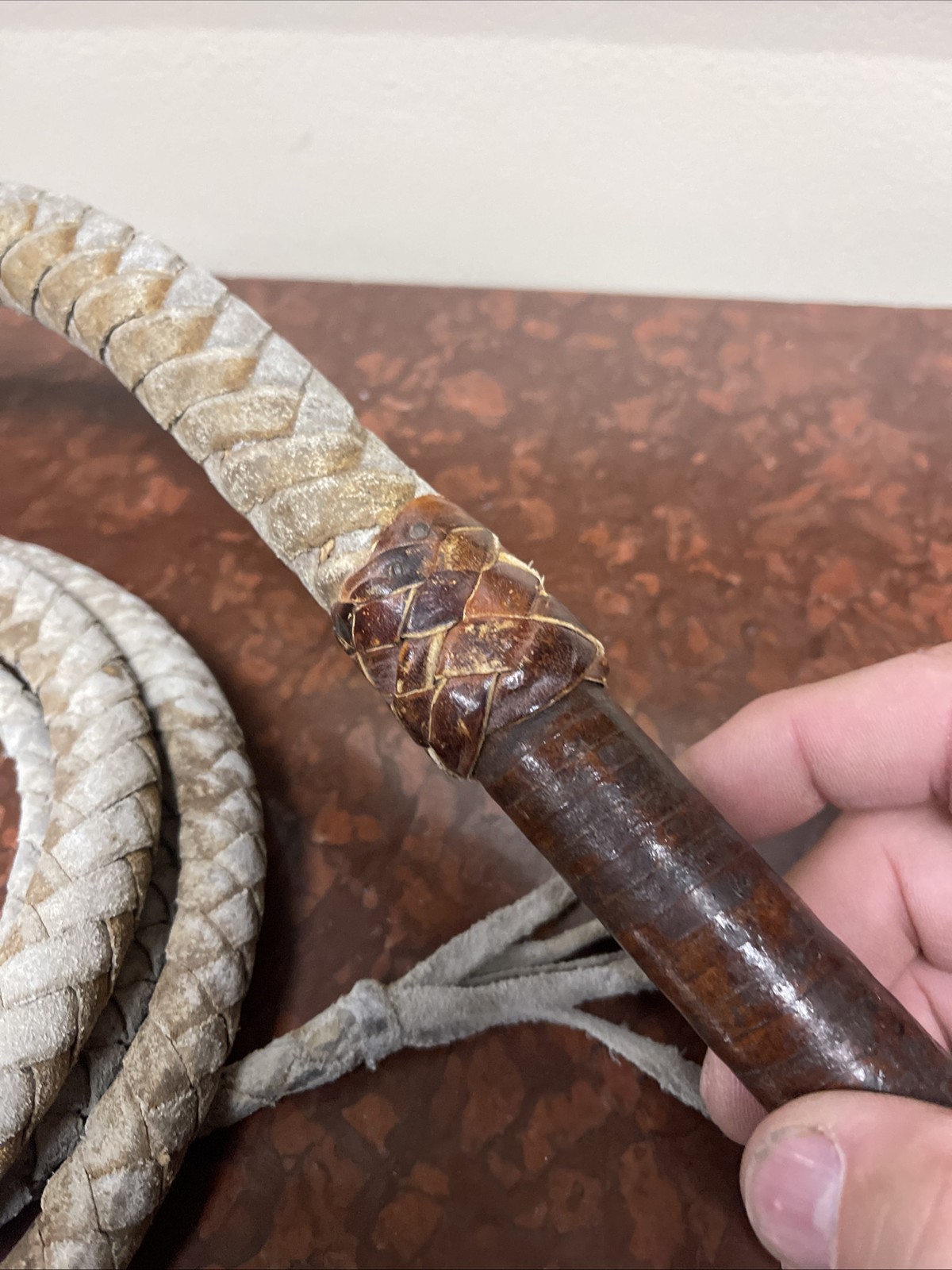 Vintage braided leather bullwhip with a patterned handle.