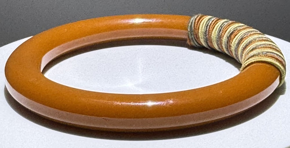Red/white/blue string-wrapped, rust-colored Bakelite bracelet; tested