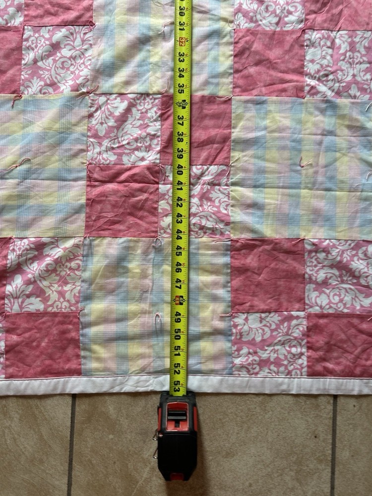Handmade patchwork quilt with floral, plaid, and pink fabrics.