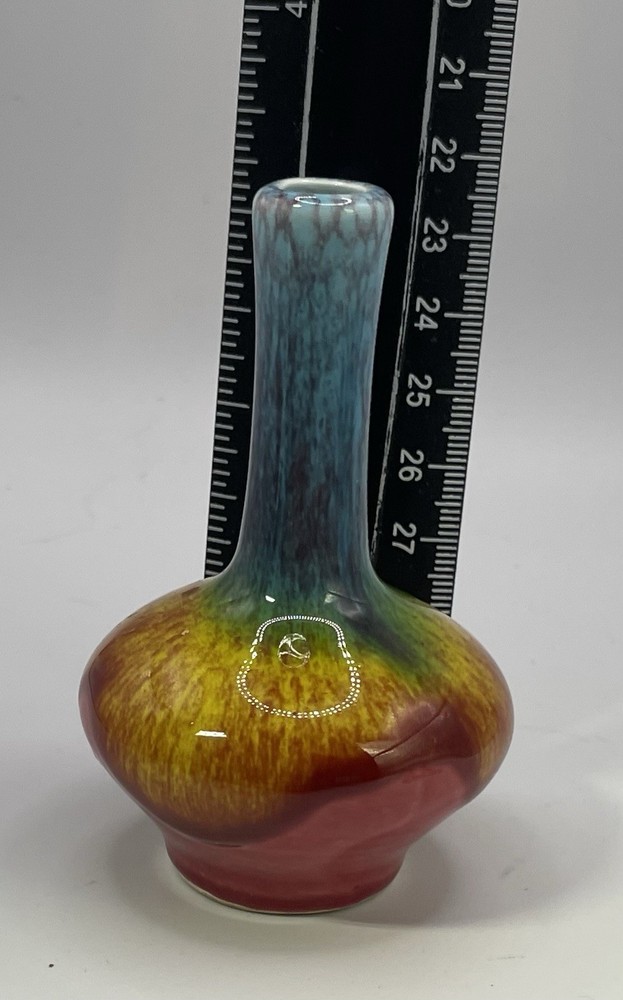 a small, multicolored, drip-glazed ceramic vase.