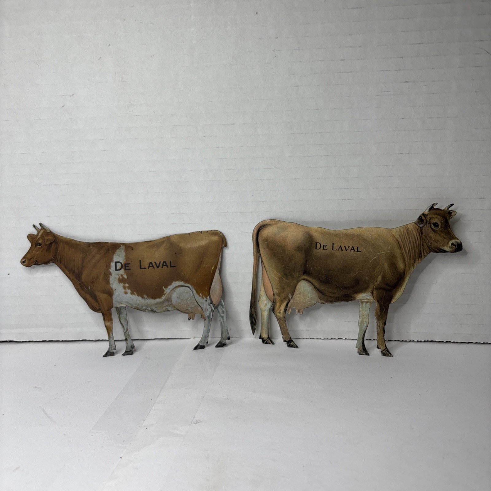 Pair of Antique DeLaval tin die cut cow and calf advertising cream separator ads