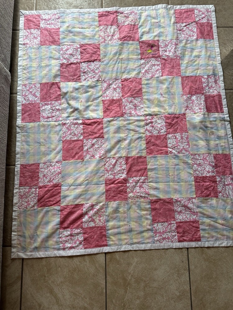 Handmade patchwork quilt with floral, plaid, and pink fabrics.