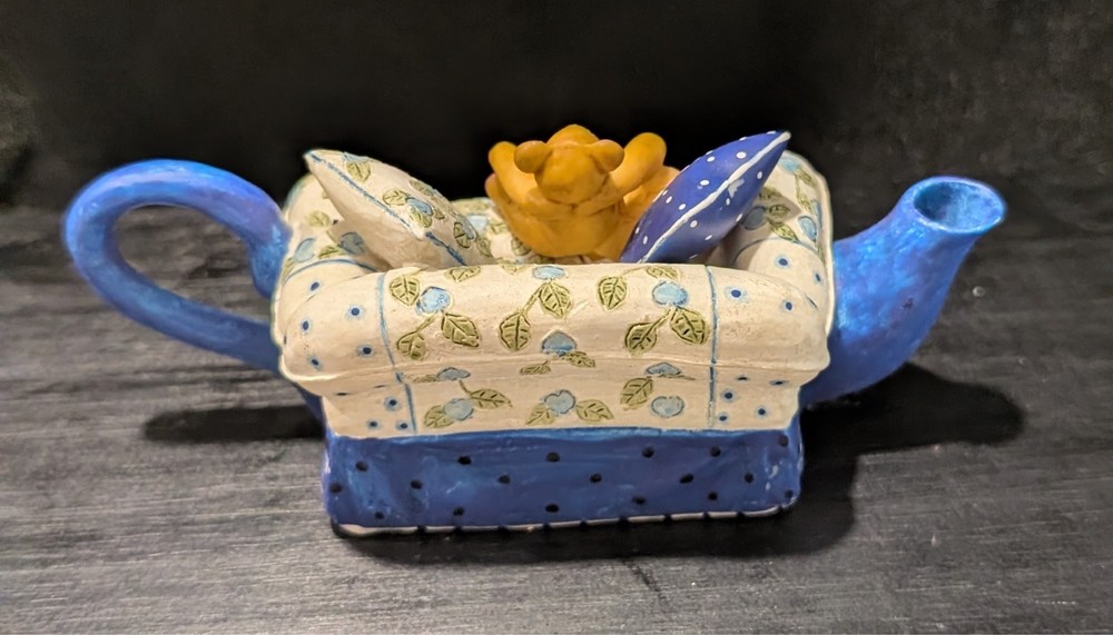 Miniature tea pot Teddy bear on couch.