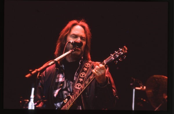 Neil Young playing guitar under red concert spotlight Original Transparency