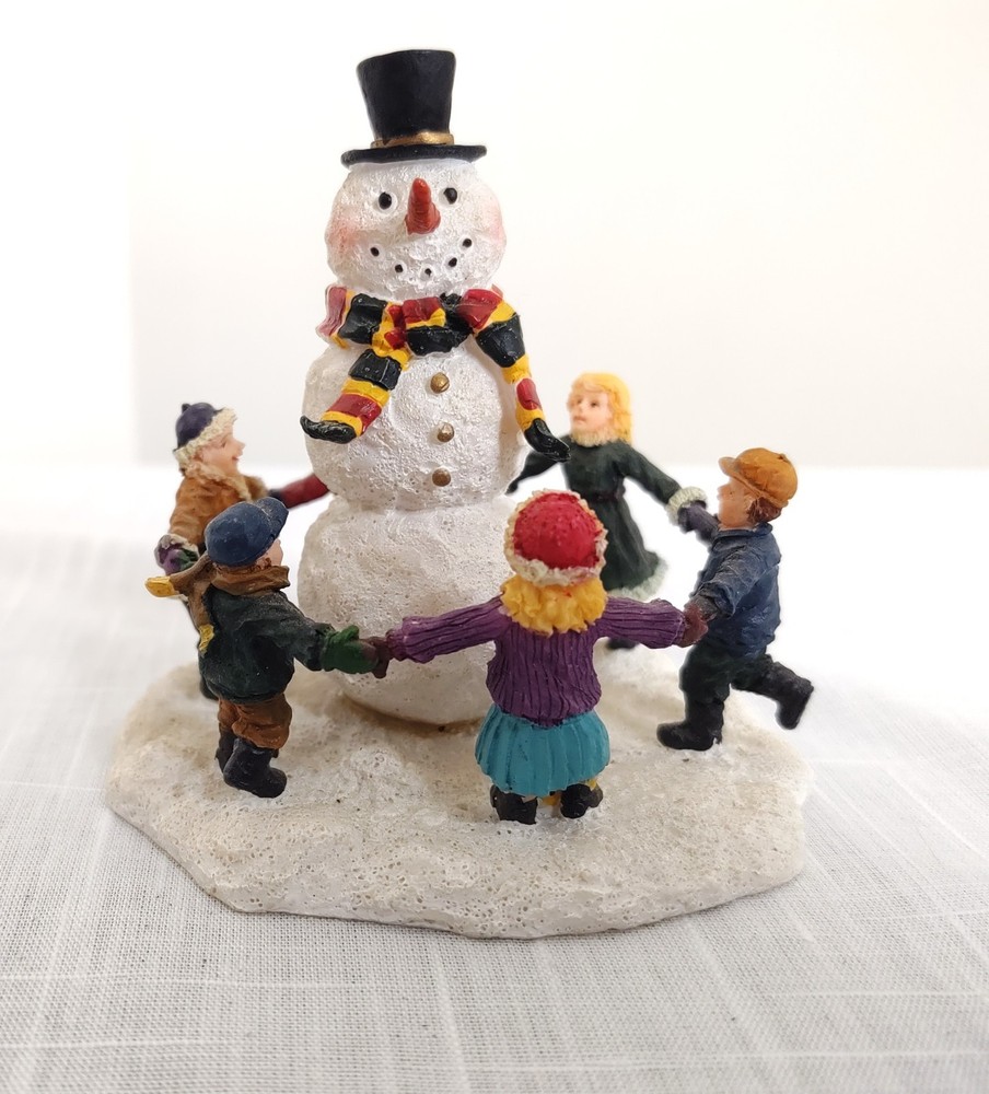 CHILDREN DANCING AROUND A SNOWMAN FIGURINE