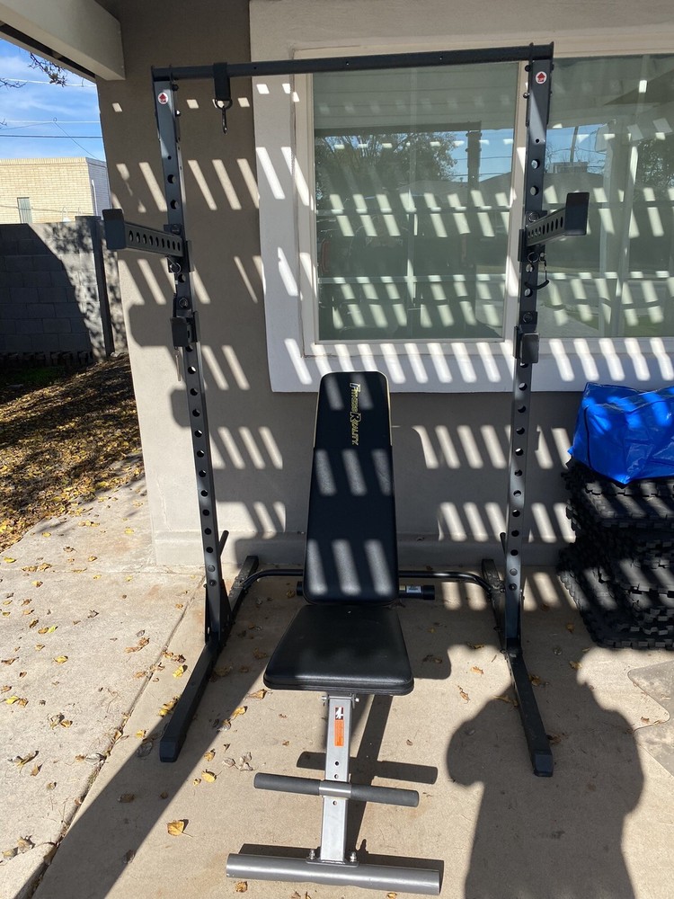 Squat Rack With Bench, Weights, Two Barbells, And A Rowing Machine