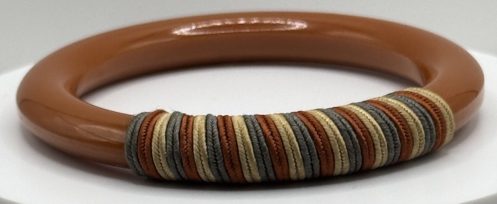 Red/white/blue string-wrapped, rust-colored Bakelite bracelet; tested