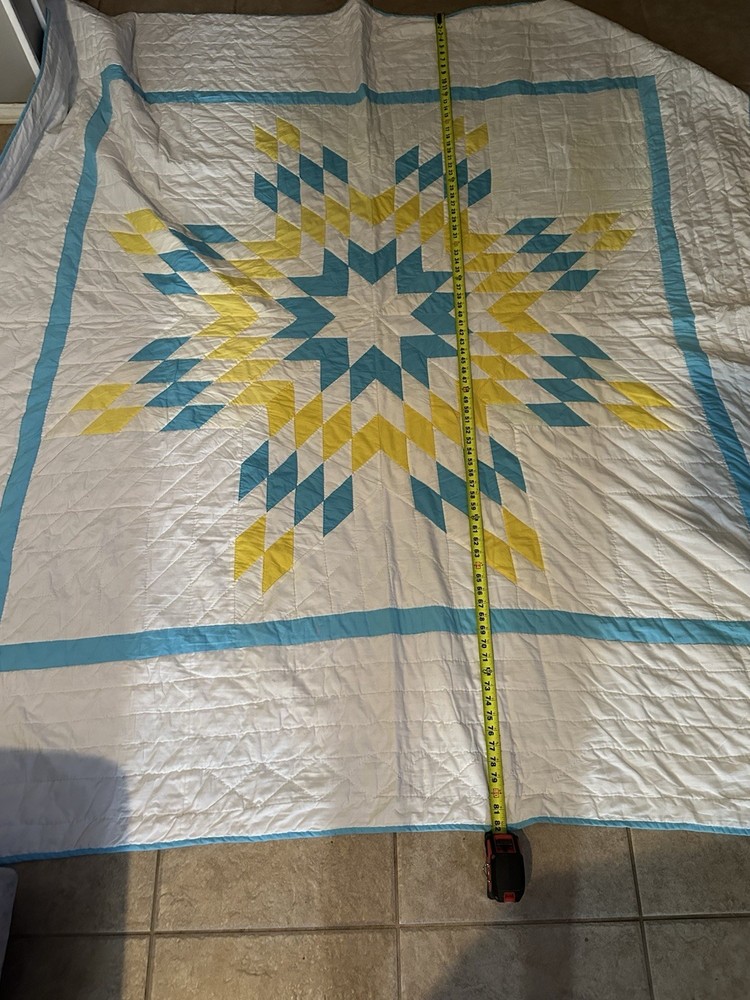 Vintage hand-stitched cotton quilt with a central star pattern.