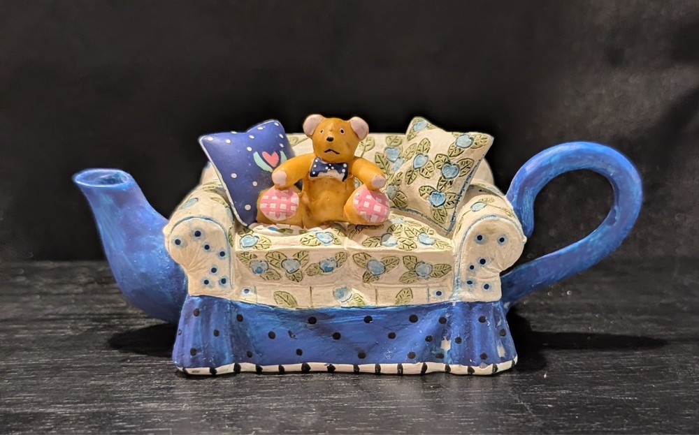 Miniature tea pot Teddy bear on couch.