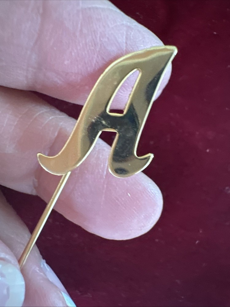 gold-tone monogram lapel pin features a cursive letter 'A' design.